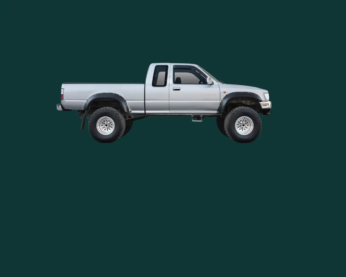 Silberner Toyota Pickup-Truck mit höhergelegtem Fahrwerk und verlängertem Fahrerhaus.